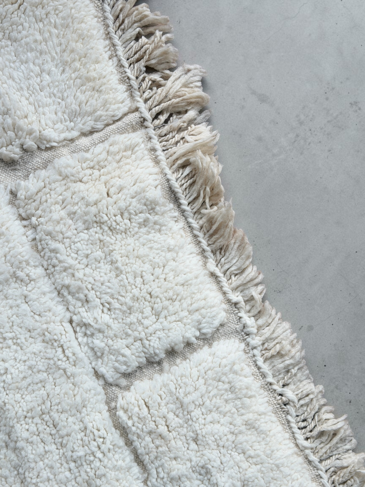Tapis Beni Ouarain YAAS en laine naturelle ivoire avec motif géométrique et franges sur un parquet en bois