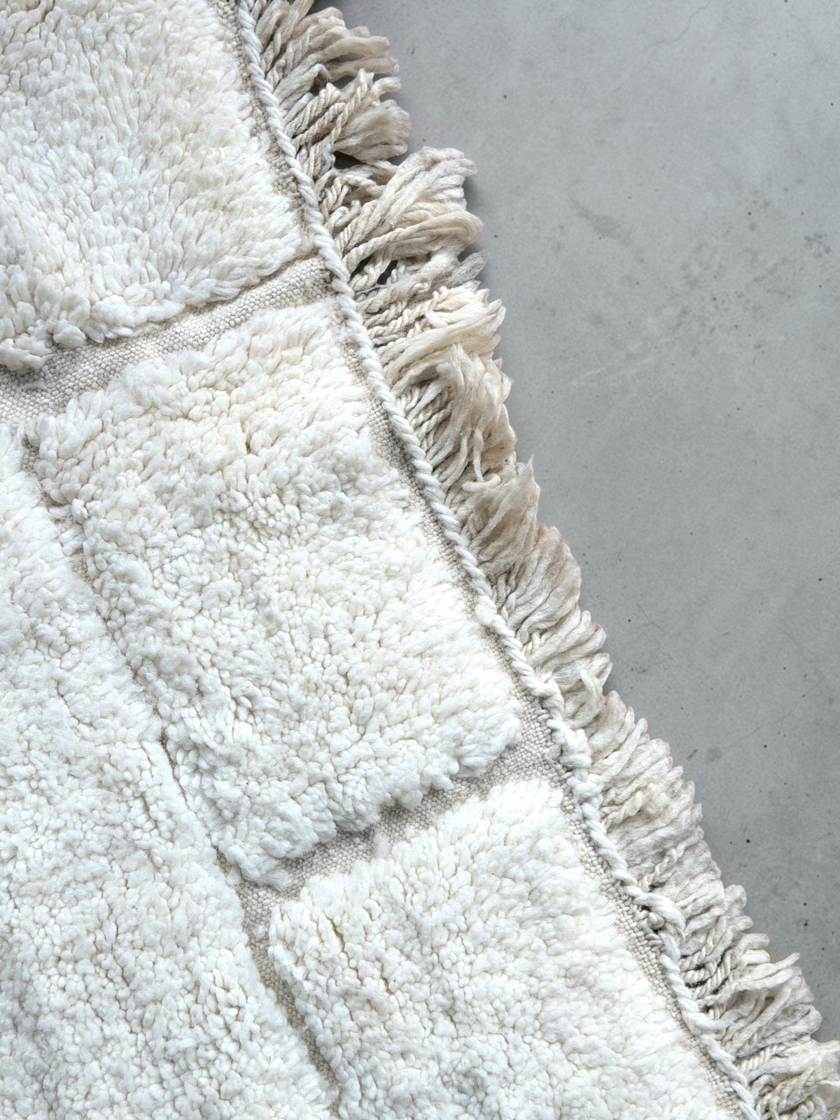 Tapis Beni Ouarain YAAS en laine naturelle ivoire avec motif géométrique et franges sur un parquet en bois
