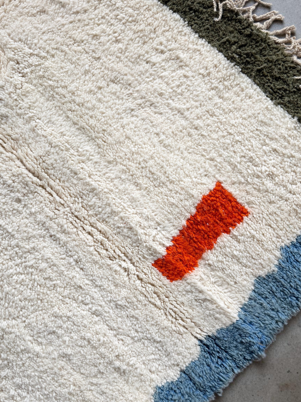 Tapis artisanal YAAS Alya en laine naturelle noué à la main avec motifs géométriques orange, bleu et vert olive