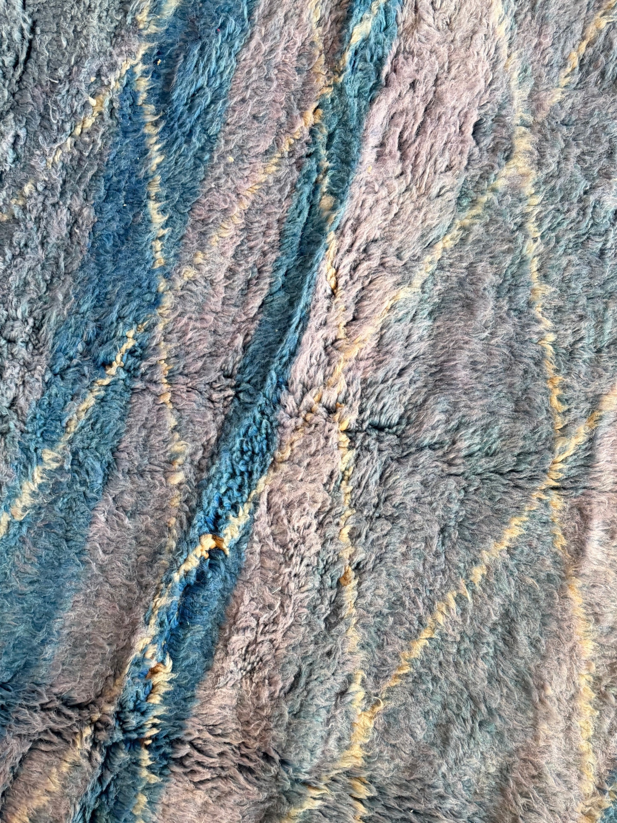 Gros plan sur un tapis YAAS Beni Ouarain en laine bleu ciel et lavande avec des motifs géométriques en losanges ivoire