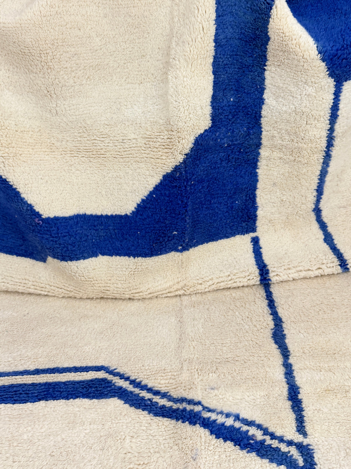 Tapis en laine de mouton YAAS x UHORAKEYE blanc cassé avec des motifs géométriques abstraits bleu vif